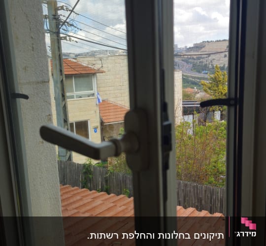 חלון פתוח עם נוף לגגות ולנוף עירוני